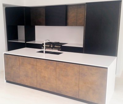 Modern kitchen with dark brown and black cabinets, a sleek white countertop, and a central island featuring a built-in sink and stovetop. Minimalist and elegant.