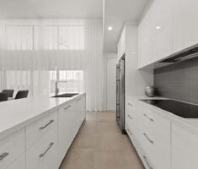“Bright galley-style kitchen with a white island and sleek cabinetry.”