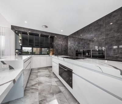 “Sleek designer kitchen with marble-style finishes and a dramatic dark feature wall.”