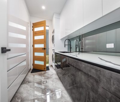 Contemporary laundry featuring high-gloss finishes, integrated storage, and a stylish timber door with frosted glass.