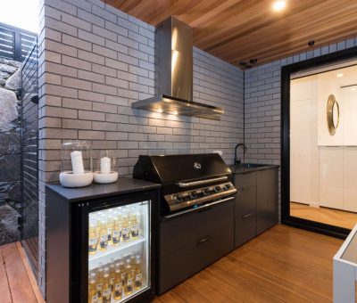 “Contemporary outdoor kitchen with BBQ, mini fridge, and stylish brick and timber finishes.”