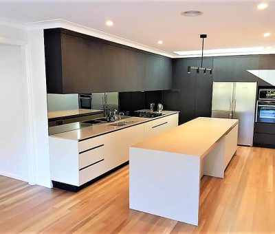 Modern kitchen with wooden floors, sleek white cabinets, stainless steel appliances, and a large central island. Minimalist, clean, and spacious.