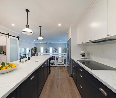 “Campbell kitchen after renovation, showcasing a bright two-tone design with elegant pendant lights and marble finishes.”