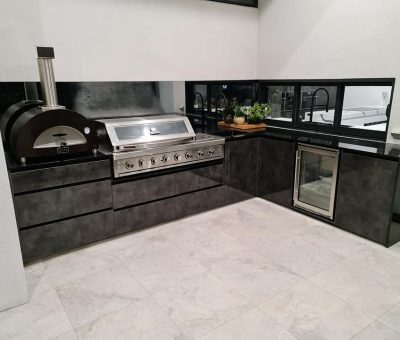 “Contemporary alfresco kitchen featuring a pizza oven, built-in BBQ, and sleek black cabinetry.”