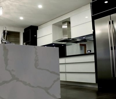 Sleek, modern kitchen with a marble island, purple under-lighting, stainless steel appliances, and white cabinets, creating a minimalist vibe.