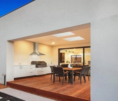 Spacious alfresco entertaining area with built-in BBQ and dining space on a timber deck.