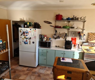 “Queanbeyan kitchen before renovation, showing dated cabinetry and cluttered layout.”