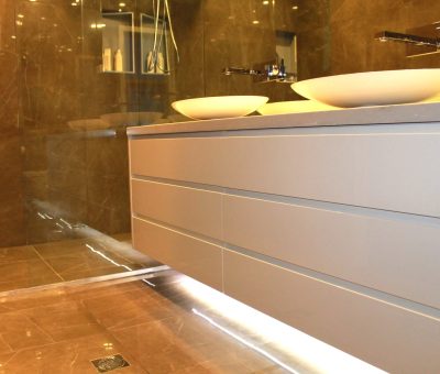 Floating bathroom vanity with dual vessel sinks, sleek drawers, and under-cabinet LED lighting.