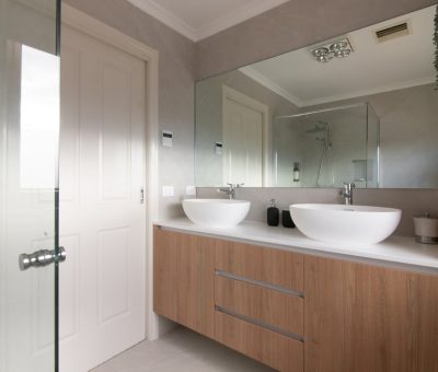 Modern bathroom with floating wooden vanity and dual basins.