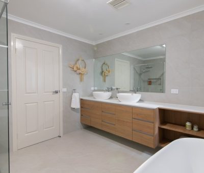 Modern bathroom with floating wooden vanity and dual basins.