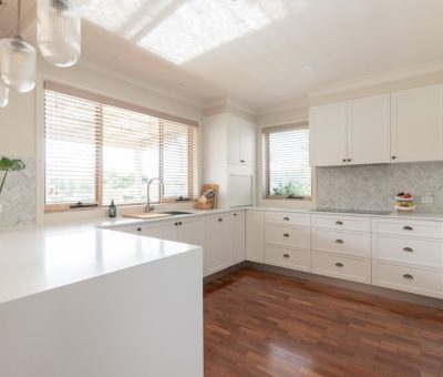 “Classic white kitchen design with abundant natural light and warm timber floors.”