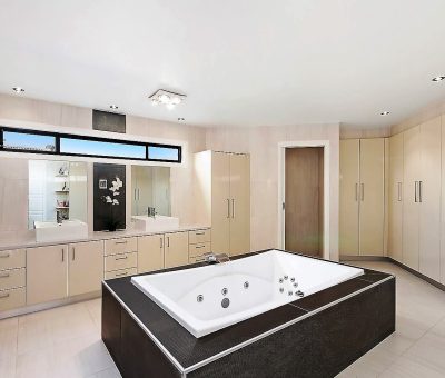 Luxurious bathroom featuring a central spa bath, double vanity, and abundant storage.