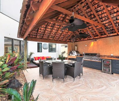 Resort-style alfresco kitchen with built-in BBQ, dining area, and lounge under a pitched tiled roof.
